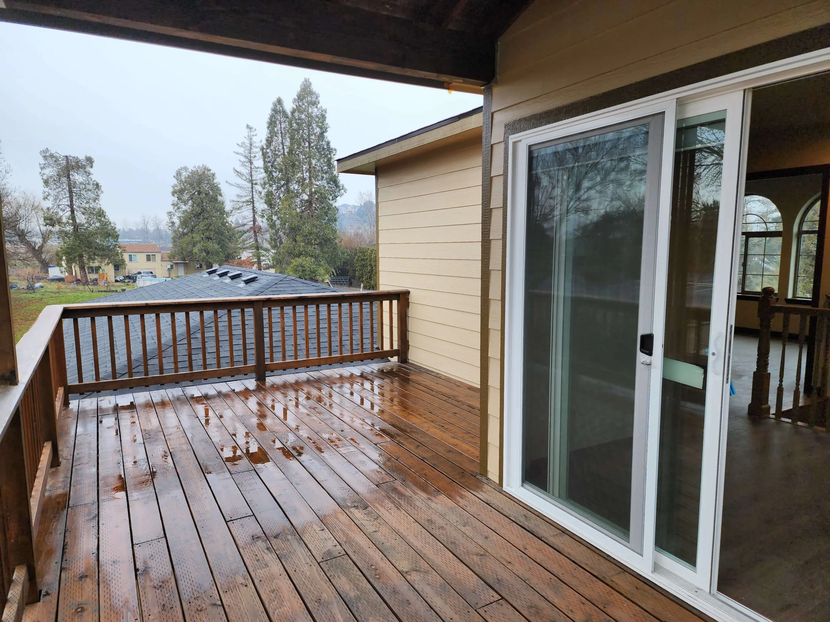 Wet wooden deck with sliding glass door.