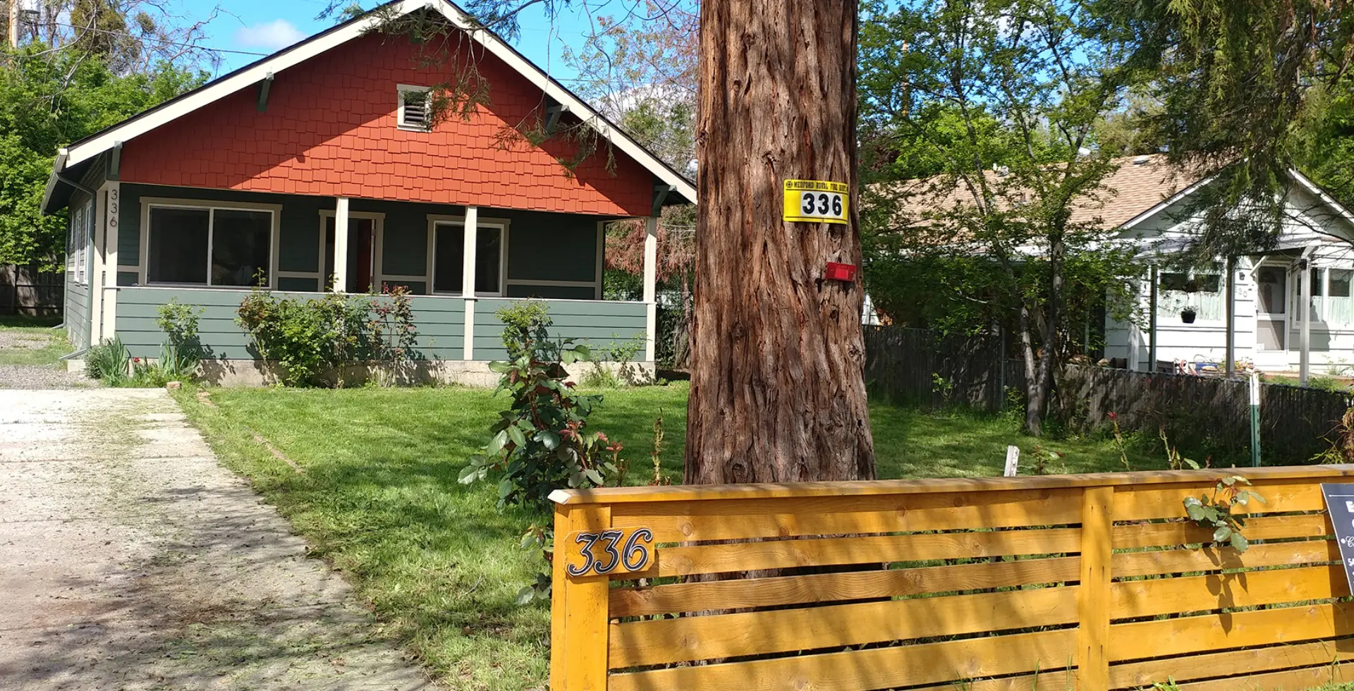 Red house with wooden fence and tree.